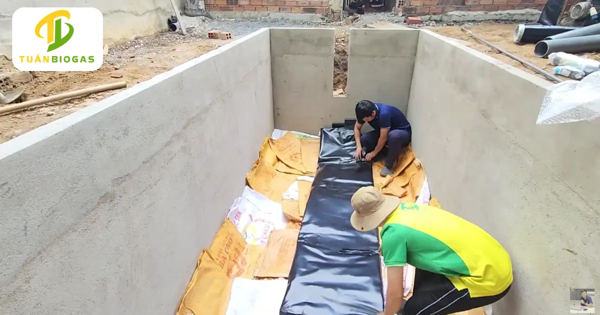 Bà con nông dân trải cuộn túi biogas tròn 8 khối nằm cân đối giữa đáy hố đất