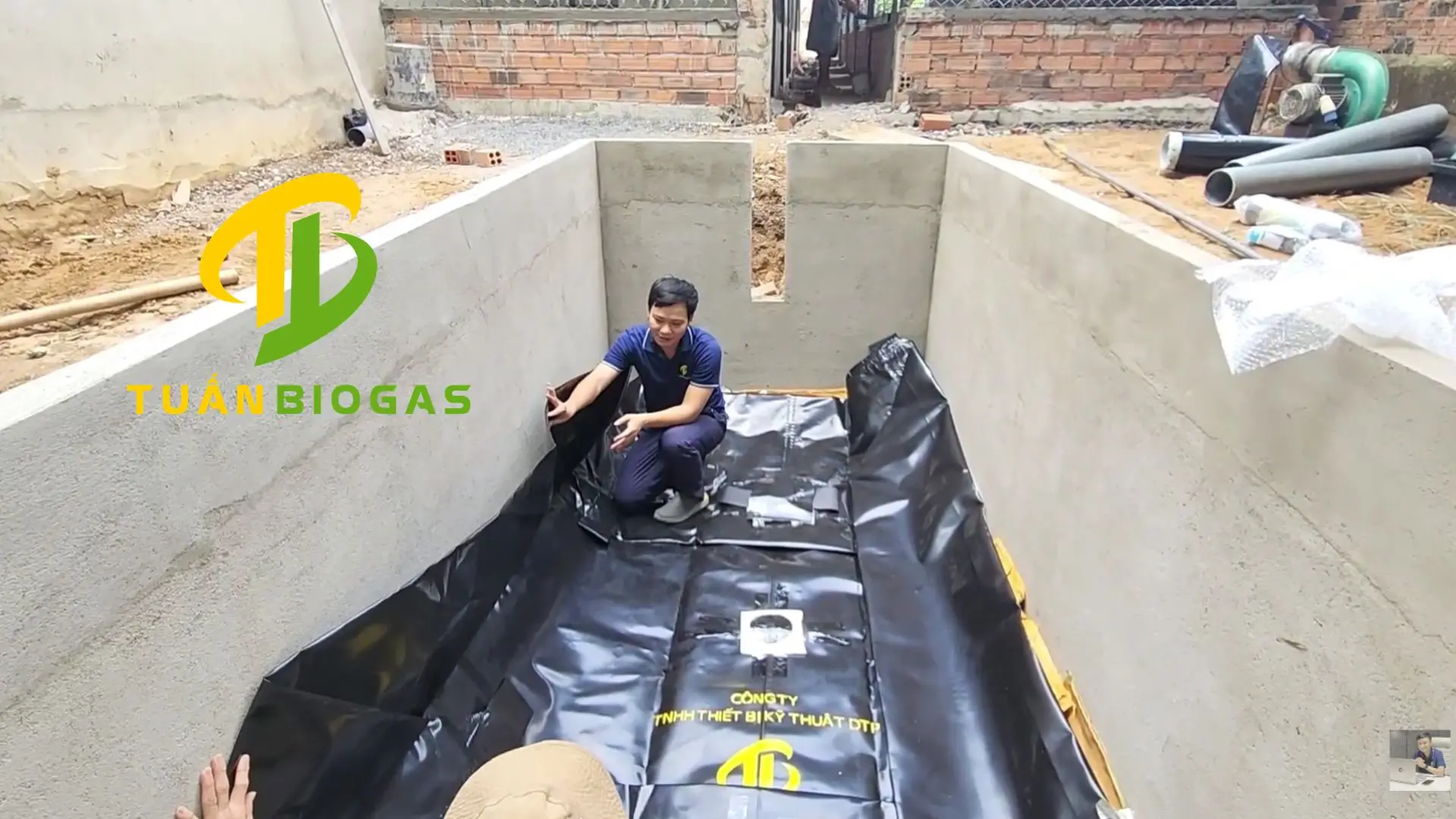 Kỹ thuật viên trải túi biogas vuông xuống hố đất phẳng đã được dọn sạch
